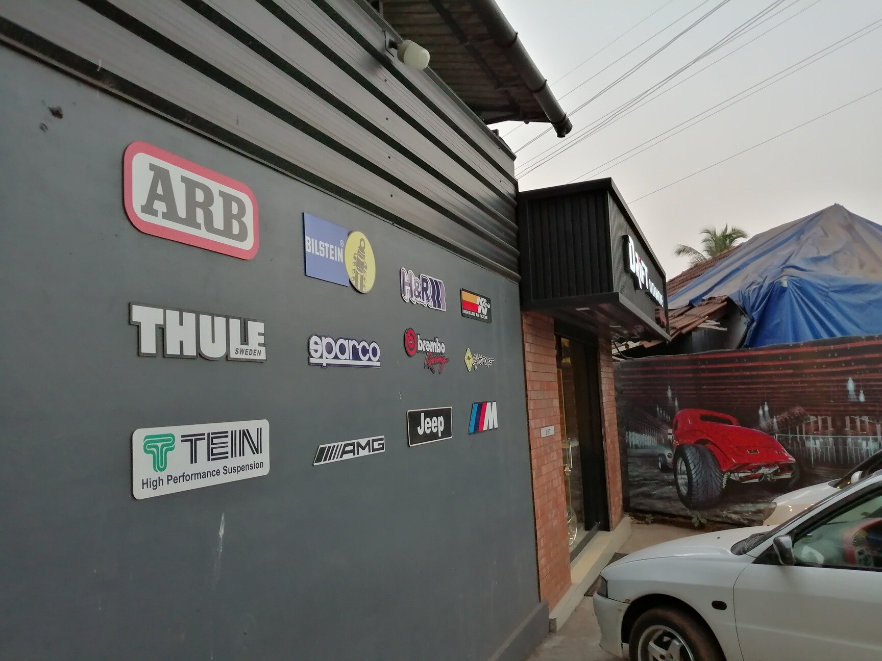 The brand wall at Drift Automotive — ARB, Bilstein, H&R, Thule, Sparco, Brembo, K&N, AMG, Jeep, BMW M, TEIN