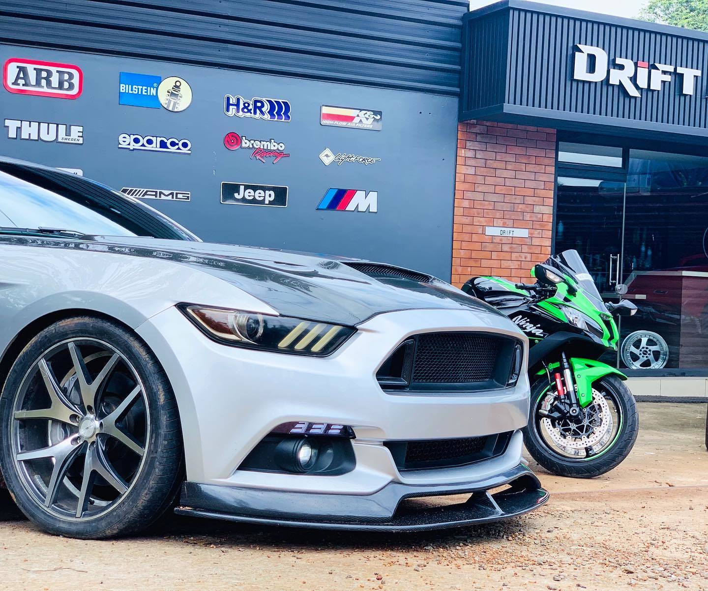 Modified Ford Mustang and Kawasaki Ninja outside the Drift Automotive workshop
